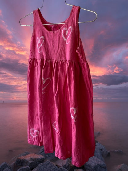 This girl's pink dress features a sleeveless design with a heart pattern making it a perfect dress for summer