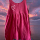 This girl's pink dress features a sleeveless design with a heart pattern making it a perfect dress for summer