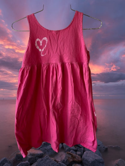 This girl's pink dress features a sleeveless design with a heart pattern making it a perfect dress for summer
