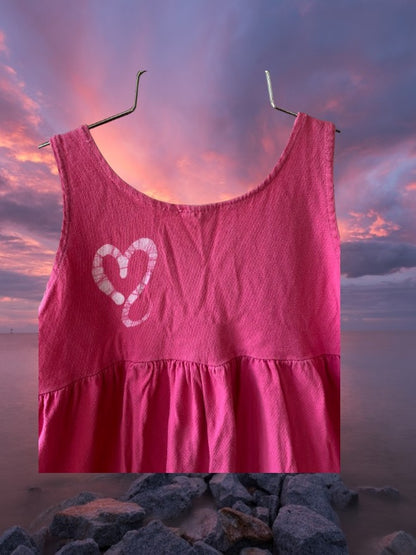 This girl's pink dress features a sleeveless design with a heart pattern making it a perfect dress for summer