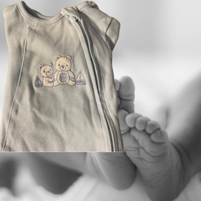 The Little Me Footed Appliqué Cotton Onesie features a charming bear appliqué design with boats